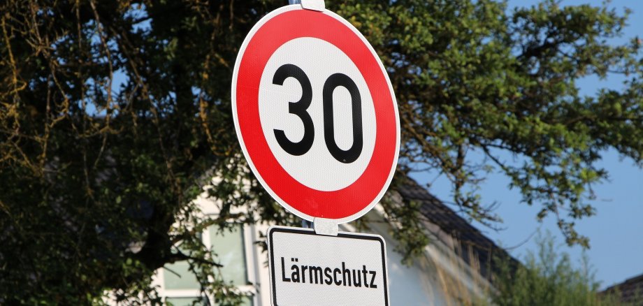 Ein Schild was auf eine "30er-Zone" hinweißt mit einem Schild wegen Lärmschutz darunter.