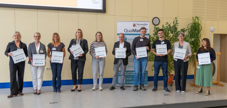 Ende September 2026 wurde die Grundschule Schweppenhausen als eine der zehn ersten Schulen im Land Rheinland-Pfalz mit dem QuaMath-Siegel ausgezeichnet. 10 Menschen, die kleine Tafeln/Hinweisschilder mit der Aufschrift QuaMath-Schule Richtung Kamera zeigen