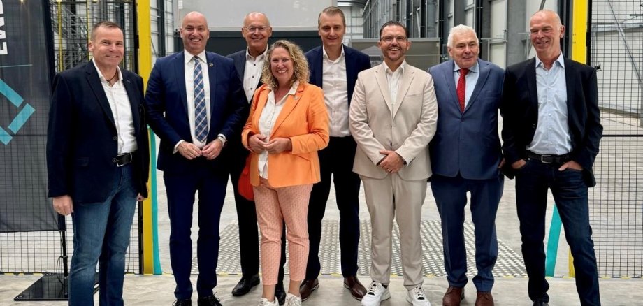 EMBEKA Technologies investiert
in moderne Logistik, Digitalisierung und weiteres Unternehmenswachstum - Ein starkes
Signal für den Wirtschaftsstandort Langenlonsheim 8 Menschen stehen lächelnd Richtung Kamera gewandt. Sie befinden sich in einer Halle, im Hintergrund stehen Container.